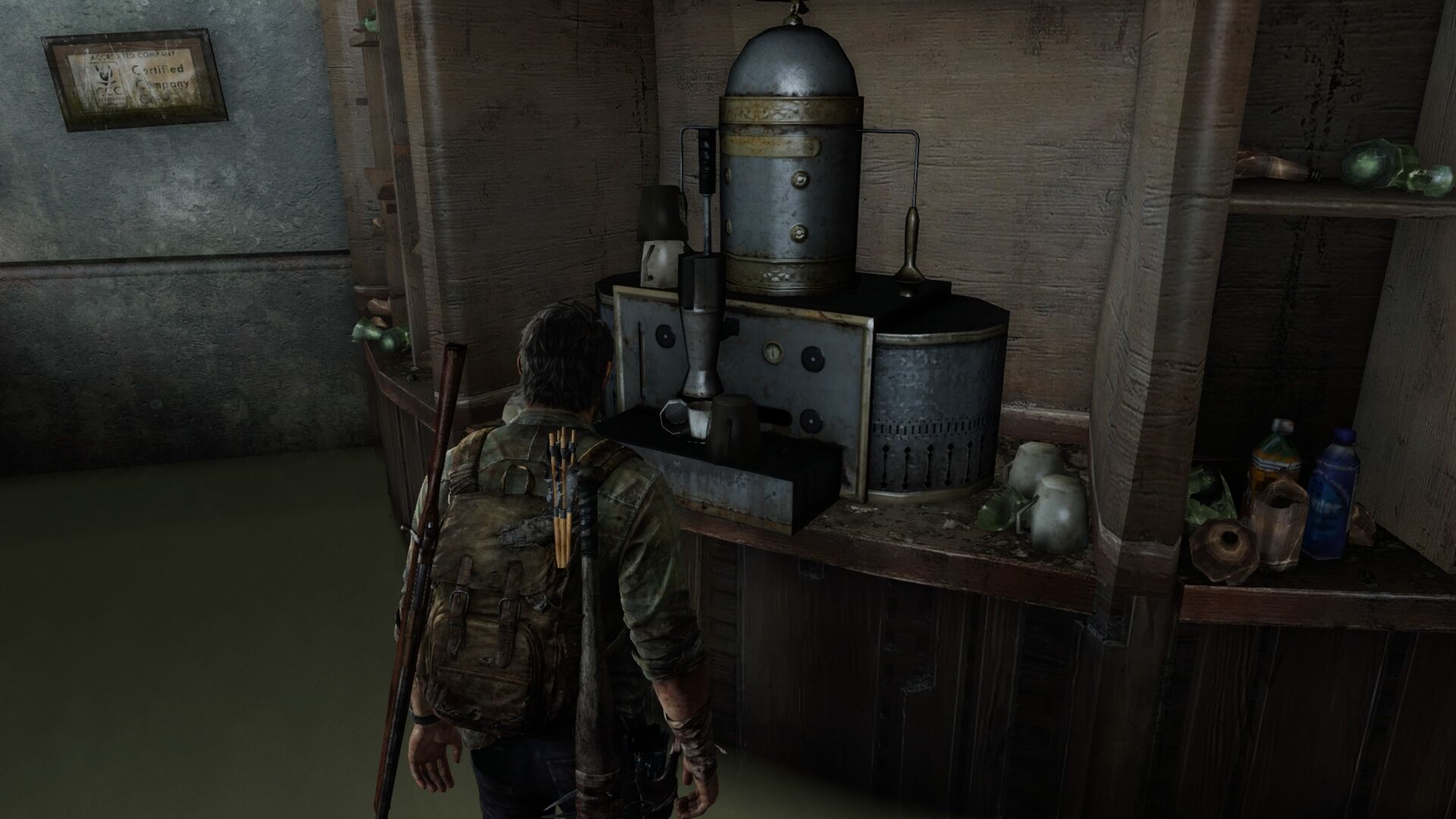 A man with a backpack and a rifle stands in front of a weathered metal machine with a cylindrical tank, multiple gauges, and a cup, inside a rustic wooden room.